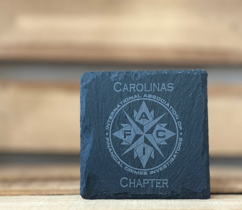 Slate coaster with 'Carolinas Chapter' and 'IAFC' logo on a wooden surface.